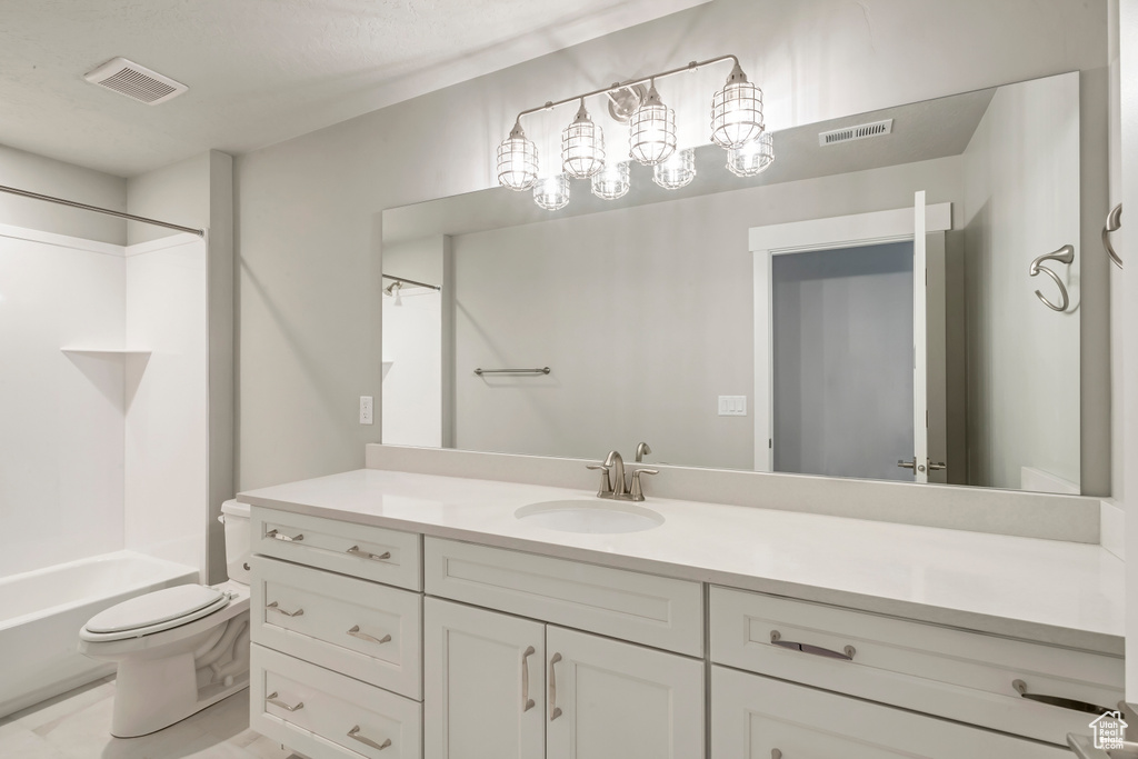 Full bathroom with toilet, tub / shower combination, and vanity with extensive cabinet space