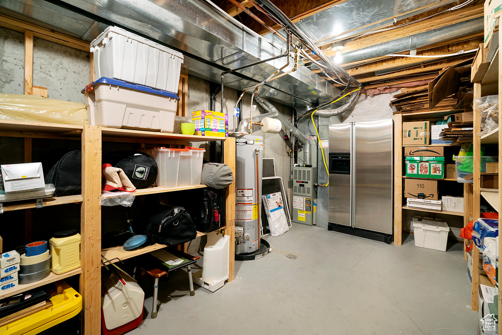 Basement featuring water heater and stainless steel fridge