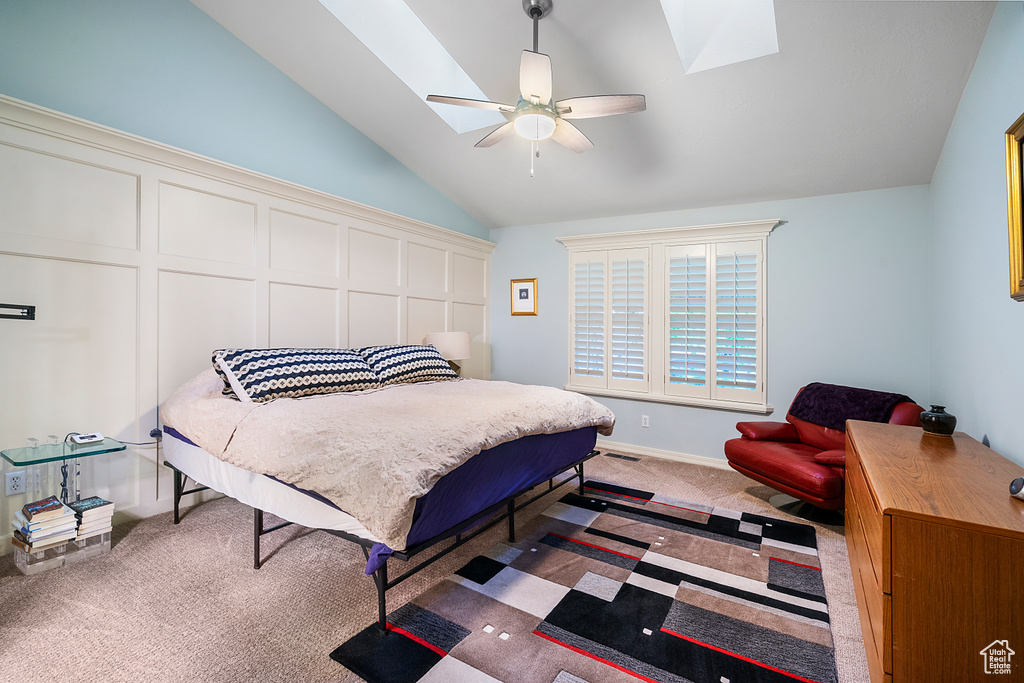 Carpeted bedroom with ceiling fan and vaulted ceiling with skylight