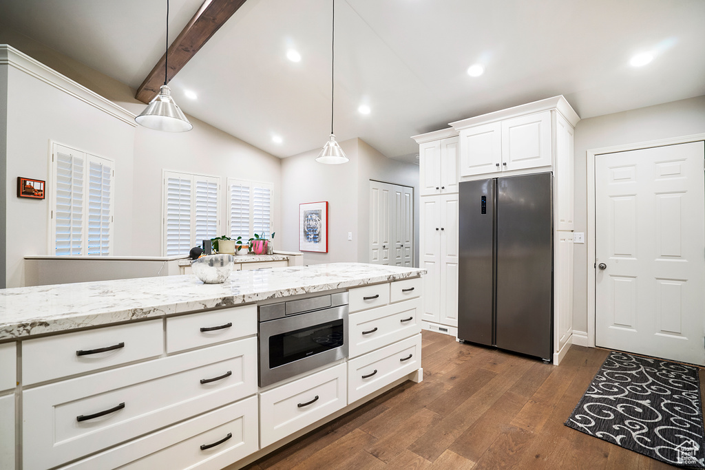 Kitchen featuring hanging light fixtures, vaulted ceiling with beams, dark hardwood / wood-style floors, stainless steel fridge, and white cabinets