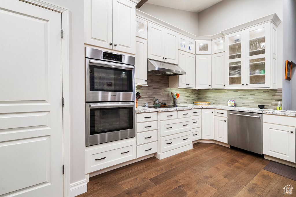 Kitchen with appliances with stainless steel finishes, dark wood-type flooring, and backsplash