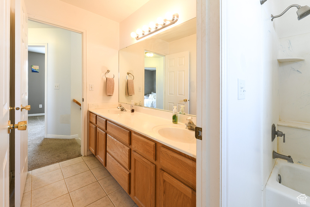 Bathroom with shower / washtub combination, dual sinks, vanity with extensive cabinet space, and tile floors