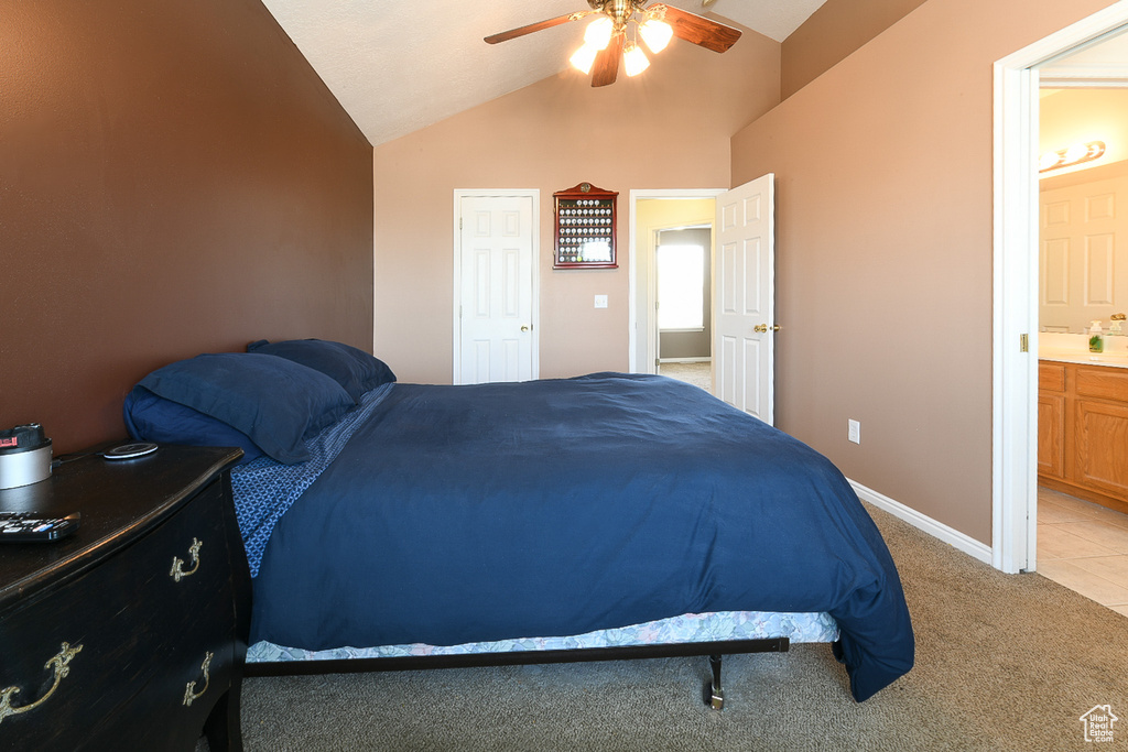 Bedroom featuring vaulted ceiling, ceiling fan, ensuite bath, and tile floors