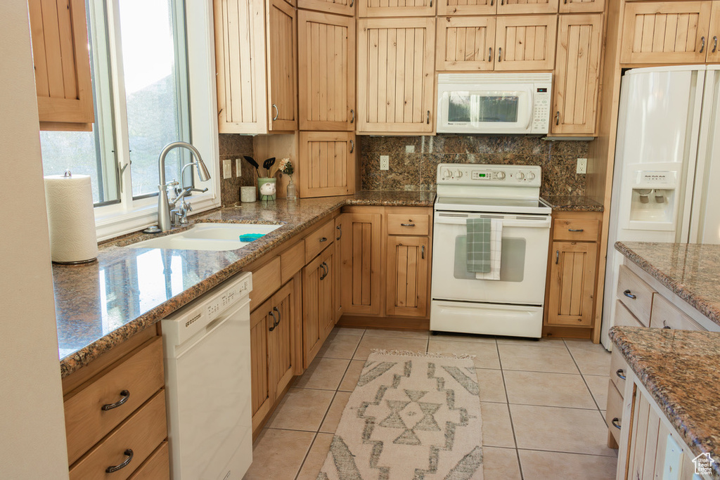 Kitchen with light tile floors, tasteful backsplash, white appliances, and sink