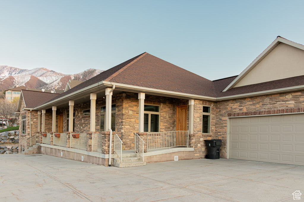 View of front of home featuring covered porch, a mountain view, and a garage