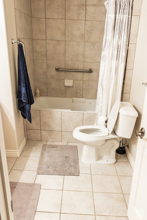 Bathroom with tile flooring, toilet, and shower / bathtub combination with curtain