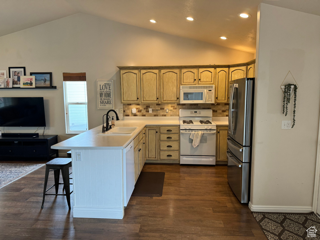 Kitchen featuring kitchen peninsula, white appliances, tasteful backsplash, a kitchen breakfast bar, and dark hardwood / wood-style flooring