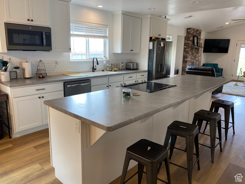 Kitchen featuring brick wall, tasteful backsplash, light hardwood / wood-style flooring, and stainless steel appliances