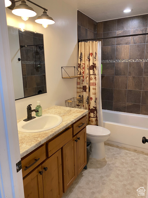 Full bathroom with tile floors, toilet, shower / bath combo, and large vanity