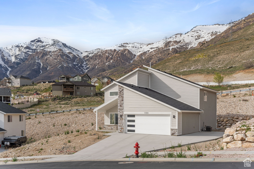 View of property with a mountain view, a garage, and central AC unit