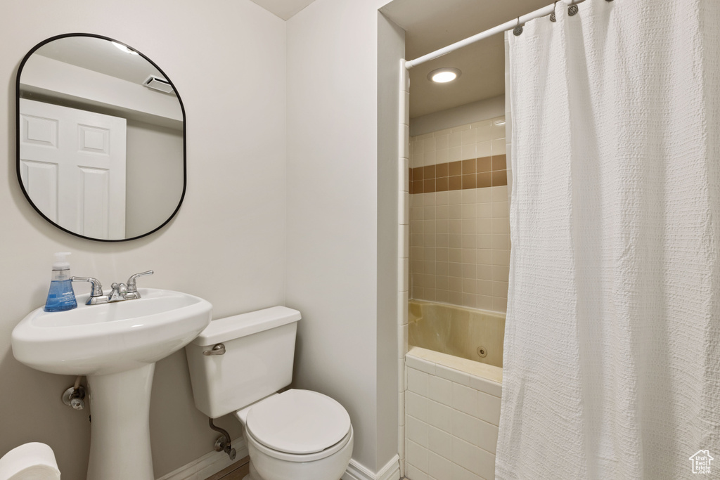 Bathroom featuring toilet and shower / bath combination with curtain