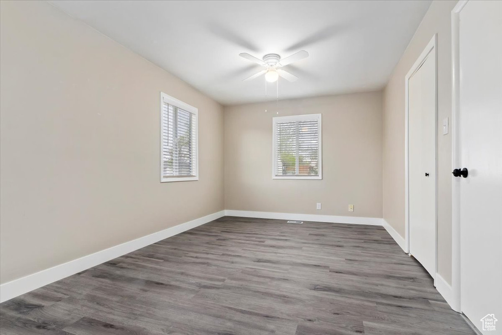 Spare room with a healthy amount of sunlight, hardwood / wood-style floors, and ceiling fan