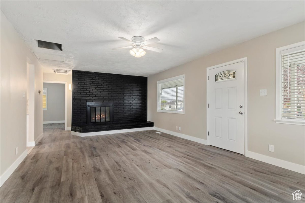 Unfurnished living room with a fireplace, ceiling fan, and hardwood / wood-style flooring