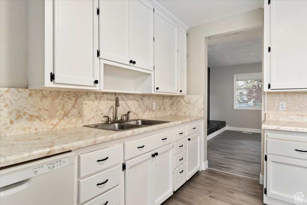 Kitchen featuring white cabinets, sink, backsplash, wood-type flooring, and white dishwasher