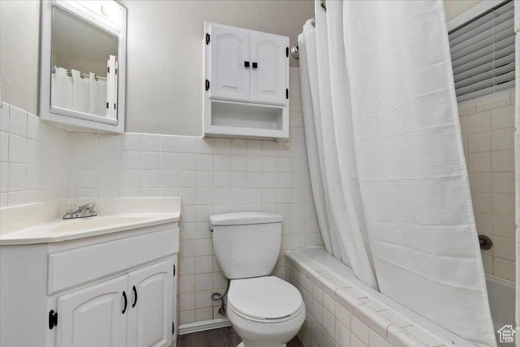 Full bathroom with shower / bath combo, tile walls, and large vanity