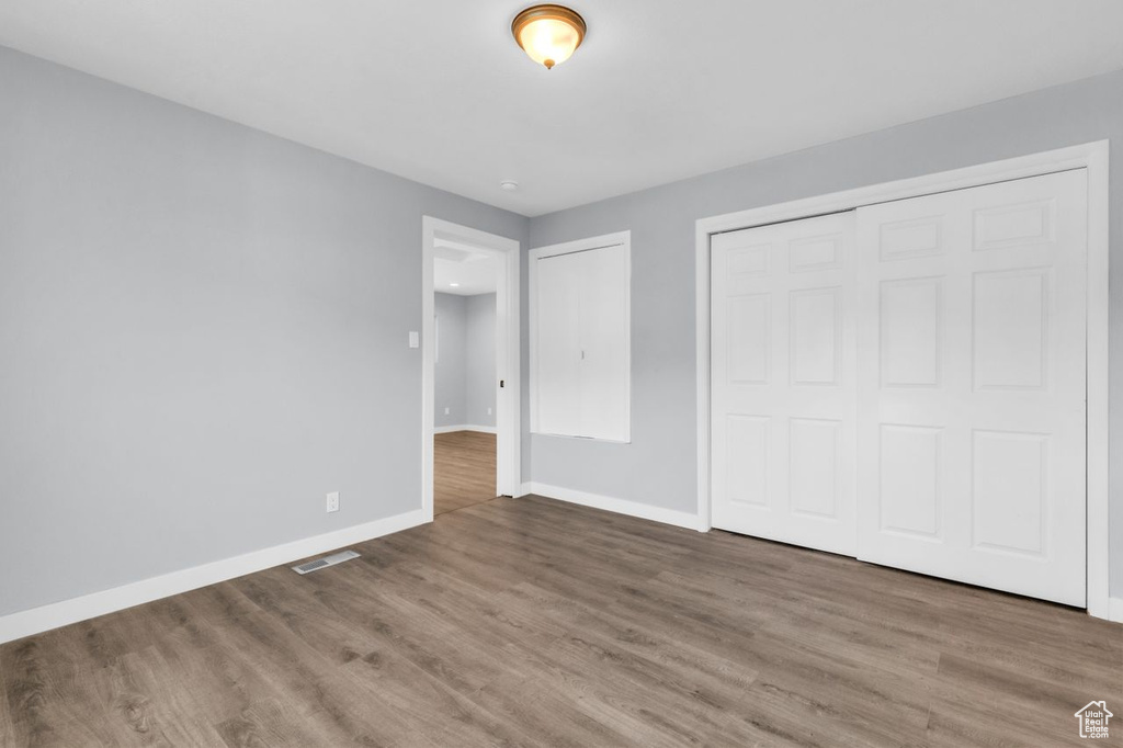 Unfurnished bedroom with a closet and hardwood / wood-style flooring