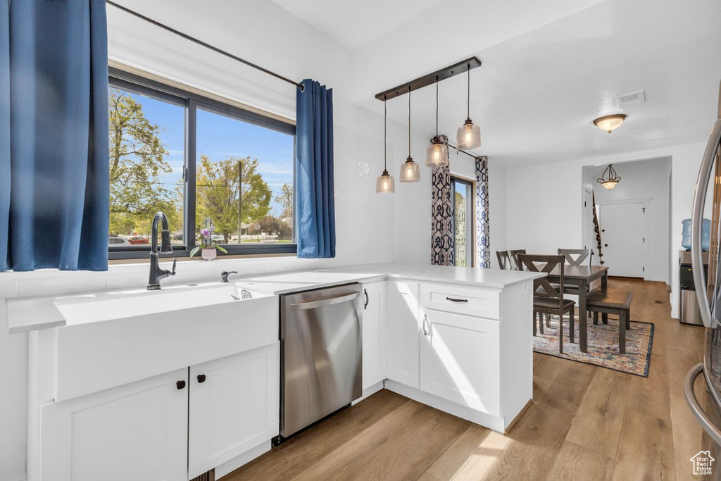 Kitchen with white cabinets, dishwasher, kitchen peninsula, and light hardwood / wood-style flooring