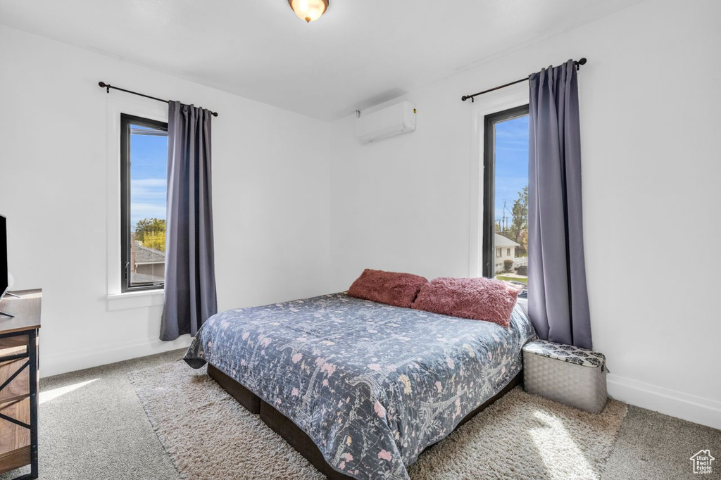Bedroom with carpet floors and a wall mounted air conditioner