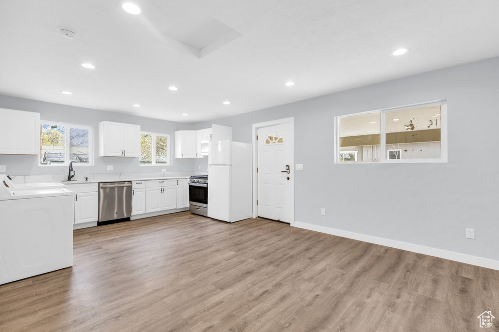 Kitchen with wood-type flooring, sink, stainless steel appliances, and white cabinets