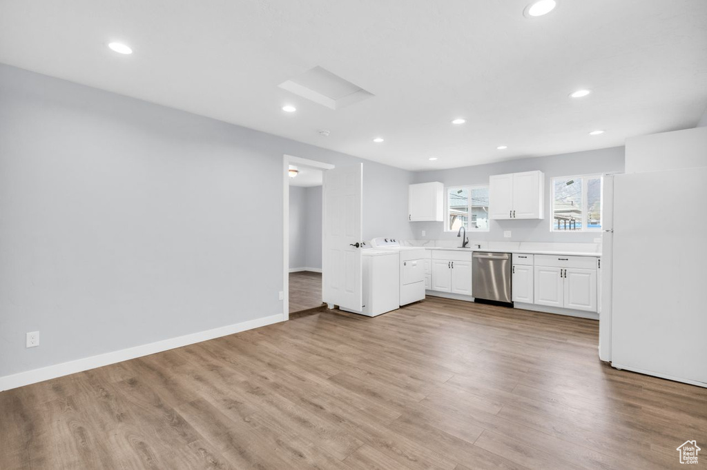Kitchen featuring white fridge, white cabinetry, hardwood / wood-style flooring, and stainless steel dishwasher