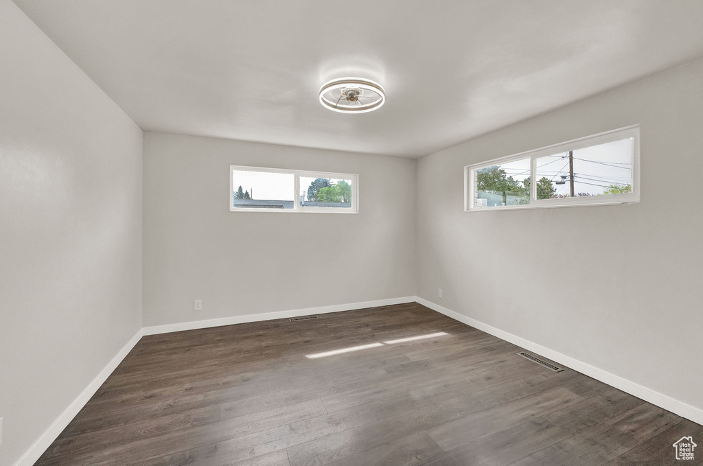 Spare room with a wealth of natural light and dark hardwood / wood-style floors