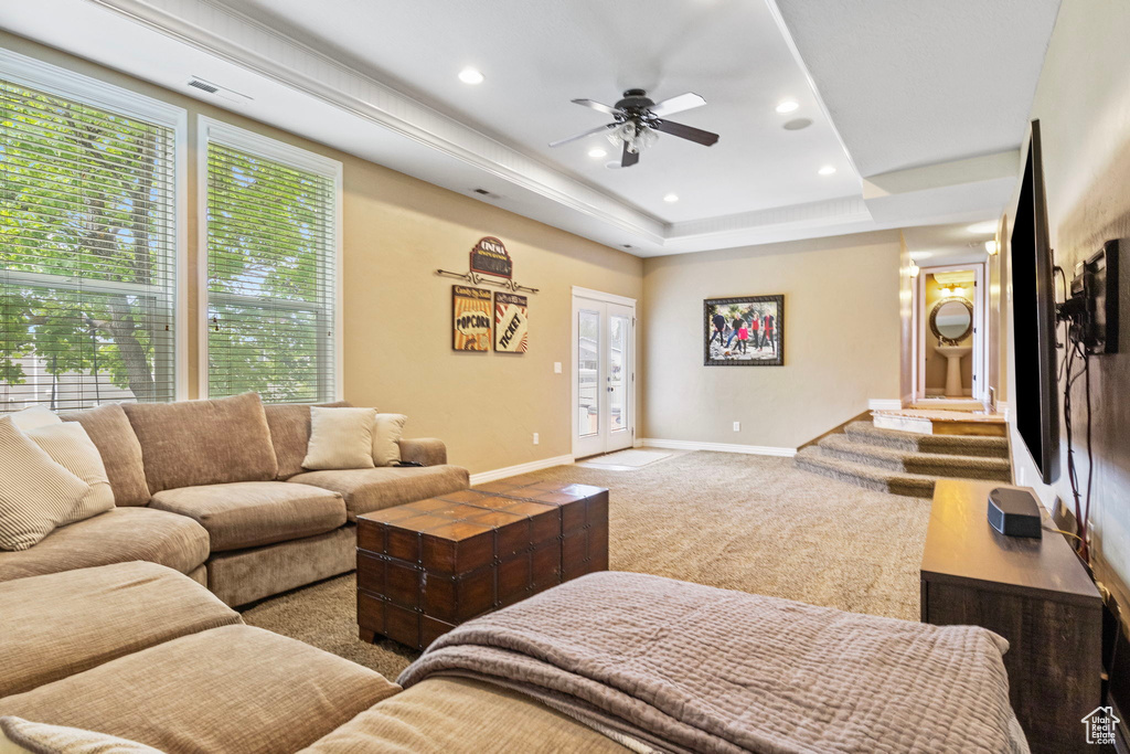 Living room featuring carpet, ceiling fan, and a tray ceiling