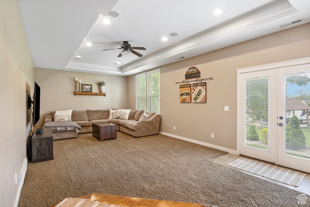 Carpeted living room featuring french doors, ceiling fan, and a tray ceiling