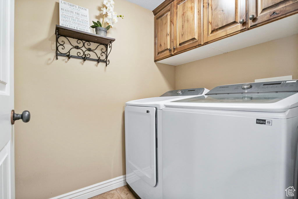 Laundry room with cabinets, light tile floors, and separate washer and dryer
