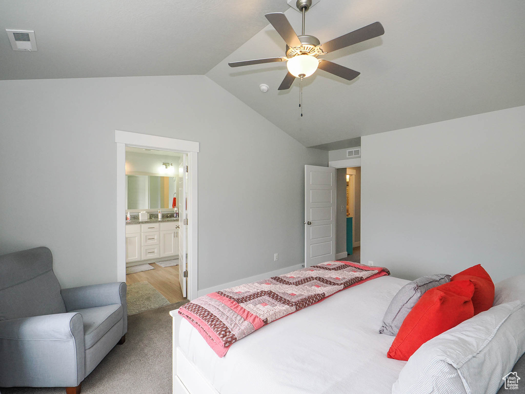 Bedroom with light colored carpet, ceiling fan, ensuite bath, and vaulted ceiling