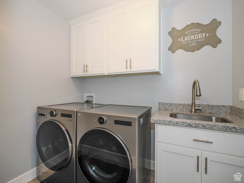Clothes washing area with washer hookup, cabinets, sink, and washer and dryer