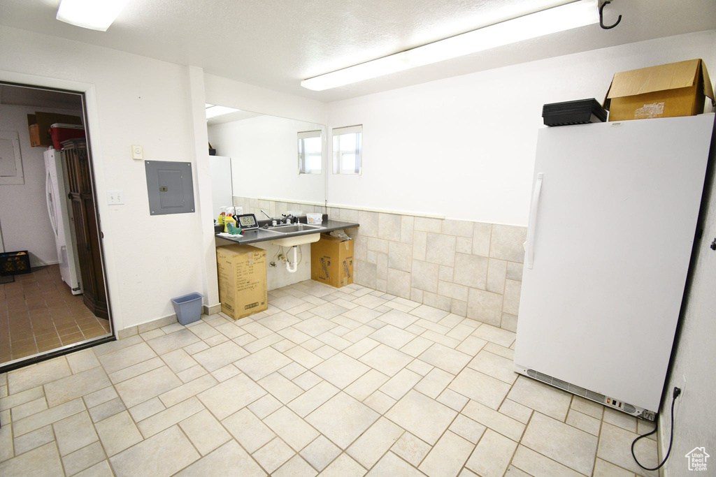 Kitchen with white fridge, light tile flooring, and tile walls