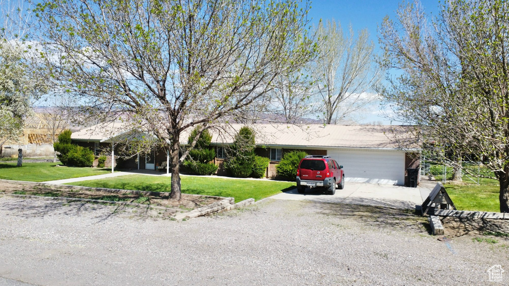 Ranch-style house featuring a garage and a front lawn