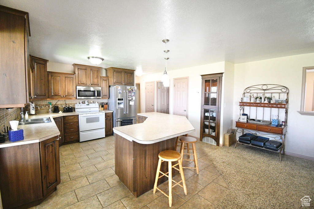 Kitchen featuring appliances with stainless steel finishes, a kitchen island, sink, backsplash, and light tile flooring