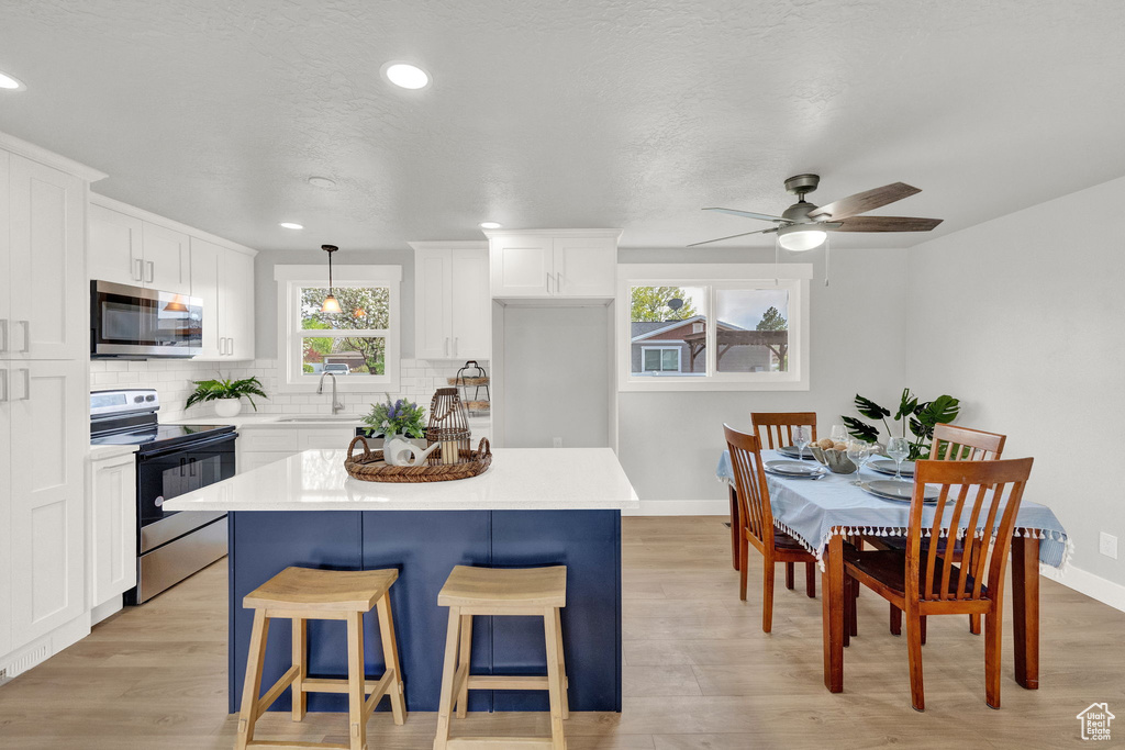 Kitchen featuring electric range, plenty of natural light, pendant lighting, and a center island