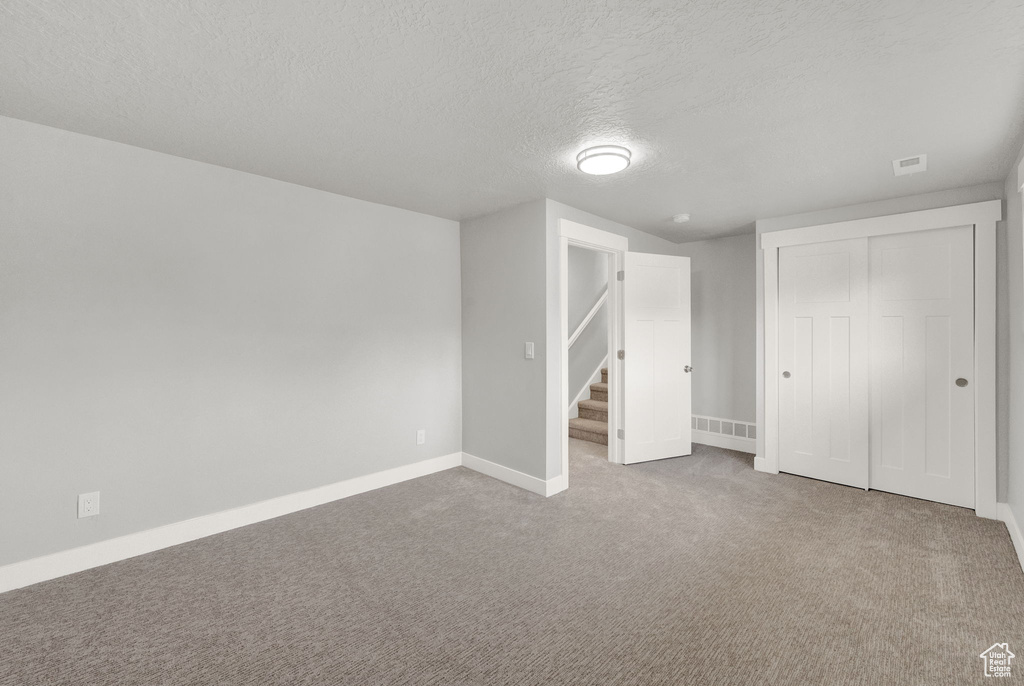 Unfurnished bedroom featuring a closet, carpet flooring, and a textured ceiling