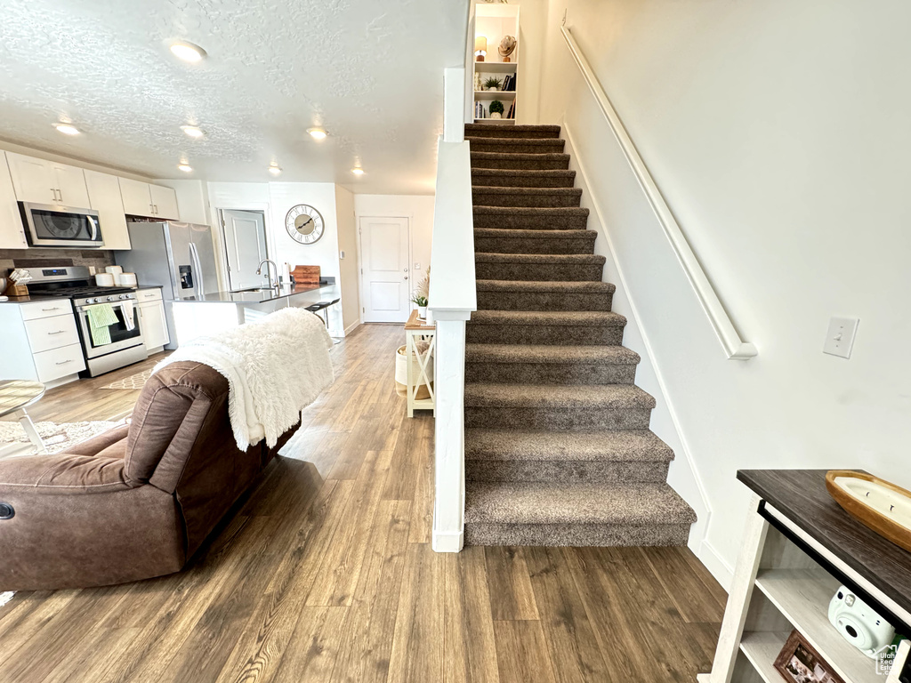 Stairs featuring hardwood / wood-style flooring, built in features, and a textured ceiling