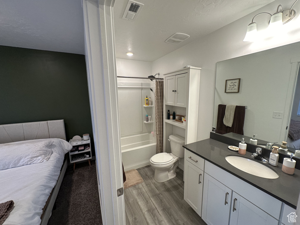 Full bathroom featuring wood-type flooring, shower / tub combo, vanity, and toilet