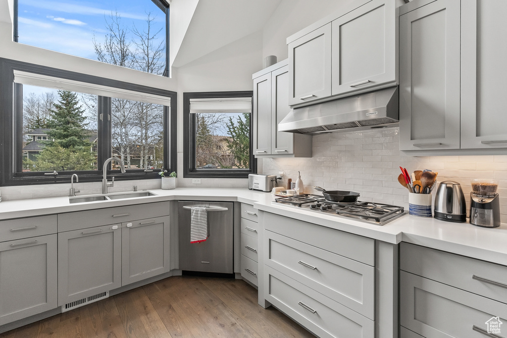 Kitchen featuring dark hardwood / wood-style flooring, stainless steel gas stovetop, vaulted ceiling, sink, and tasteful backsplash