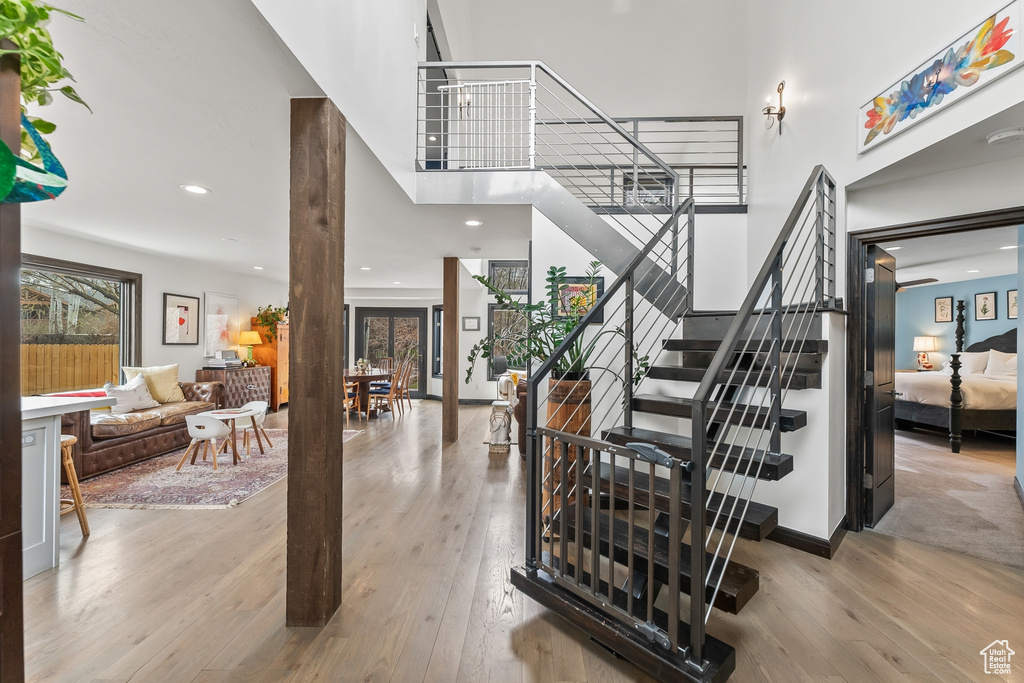 Stairs with light hardwood / wood-style flooring and a high ceiling