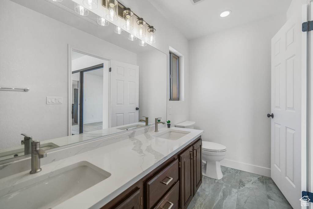 Bathroom featuring toilet, tile flooring, and dual vanity