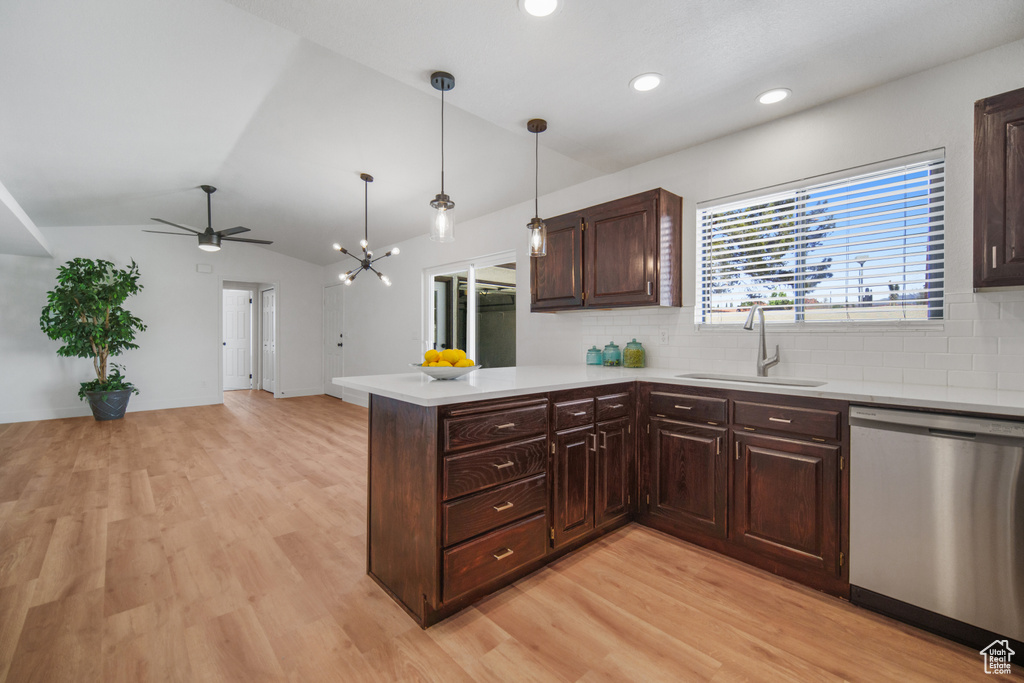Kitchen with lofted ceiling, tasteful backsplash, pendant lighting, light wood-type flooring, and stainless steel dishwasher