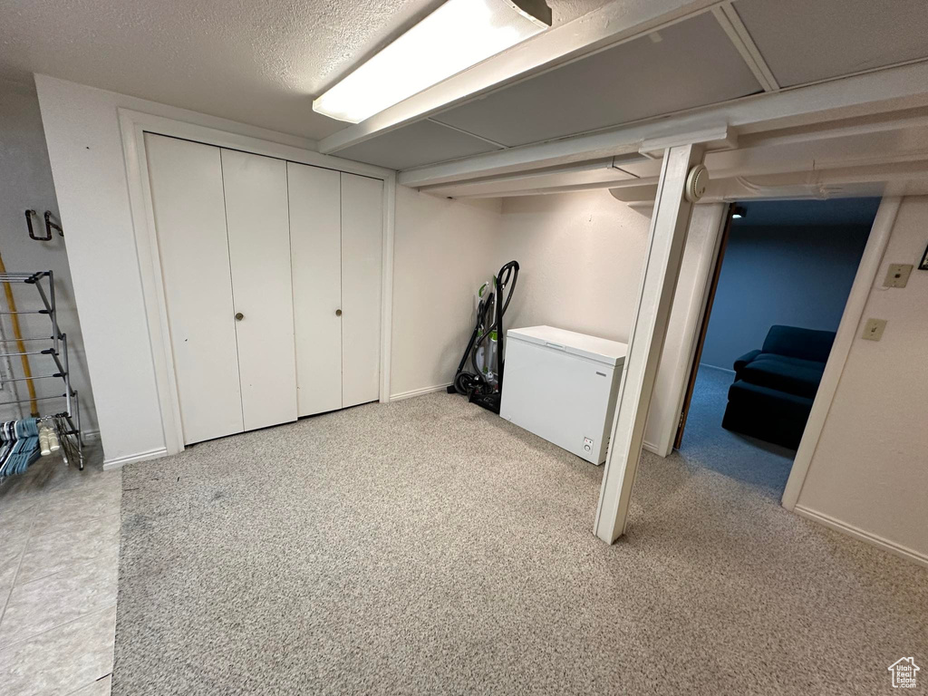Basement with fridge and a textured ceiling