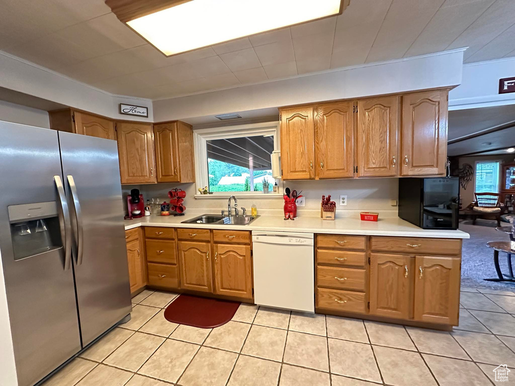 Kitchen featuring sink, dishwasher, light tile floors, and stainless steel refrigerator with ice dispenser