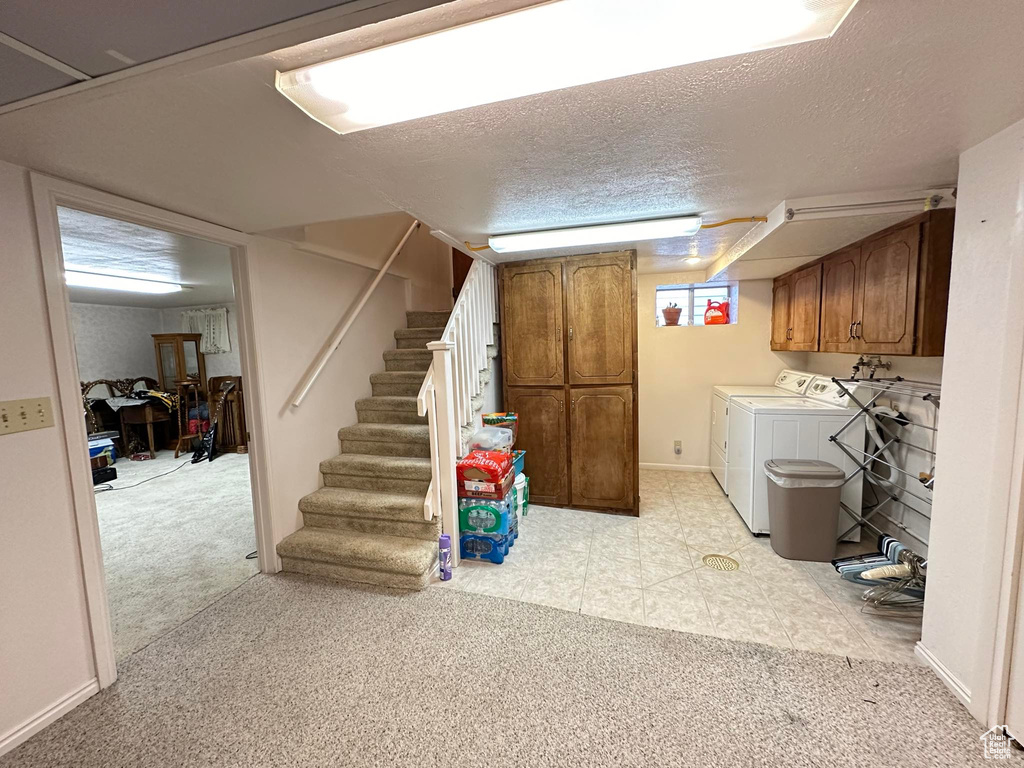 Basement featuring light carpet, washing machine and dryer, and a textured ceiling