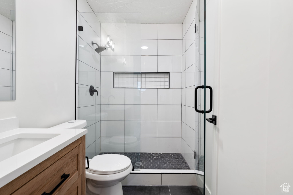 Bathroom featuring walk in shower, vanity, toilet, and tile flooring