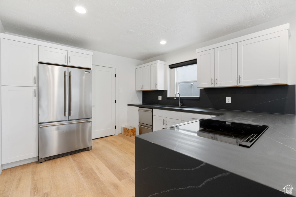Kitchen with backsplash, white cabinetry, built in fridge, and light wood-type flooring