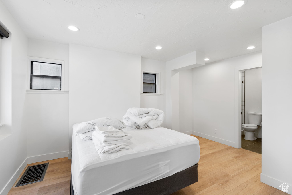 Bedroom with light hardwood / wood-style floors and connected bathroom