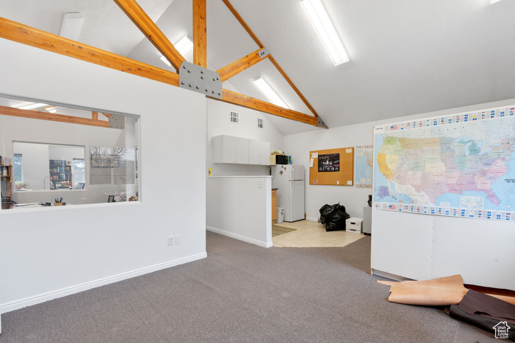 Interior space with high vaulted ceiling, light colored carpet, and beam ceiling