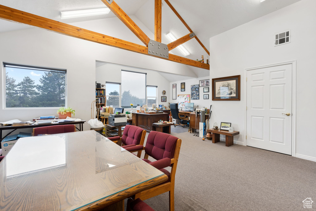 Carpeted dining room featuring beamed ceiling and high vaulted ceiling