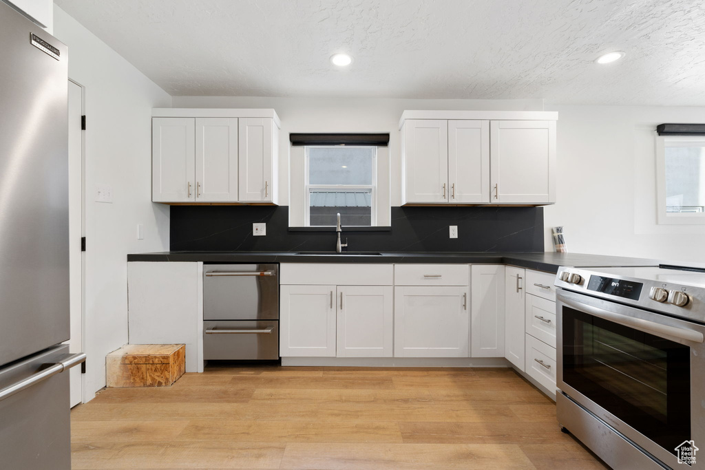 Kitchen featuring sink, appliances with stainless steel finishes, white cabinetry, and a wealth of natural light